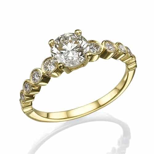טבעת זהב אלגנטית עם יהלום מרכזי בחיתוך עגול ויהלומים קטנים יותר משובצים לאורך הרצועה.