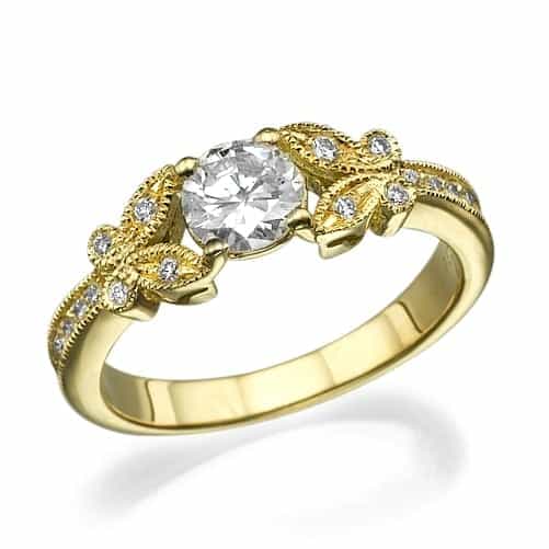 טבעת זהב צהוב אלגנטית הכוללת יהלום מרכזי בחיתוך עגול, כשלצידה עיצובי פיליגרן מורכבים ומעוטרת ביהלומי הדגשה קטנים יותר.