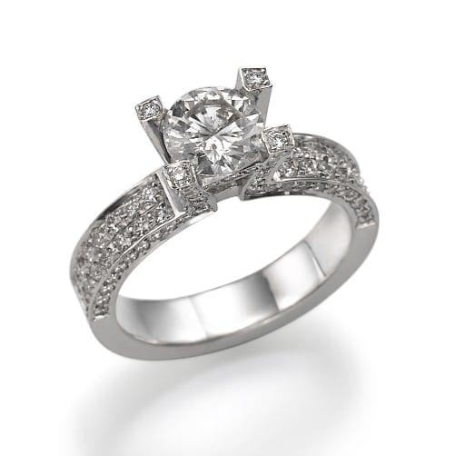 טבעת אירוסין בצבע כסף עם יהלום מרכזי גדול בחיתוך עגול ובצדו אבנים קטנות יותר ורצועת יהלומים משובצת פאווה.