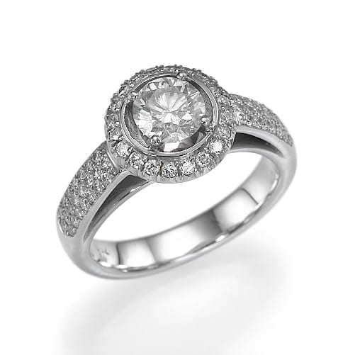 טבעת אירוסין נוצצת בליטוש עגול עם שיבוץ הילה ויהלומי פאווה לאורך הרצועה, המוצגת על רקע לבן.