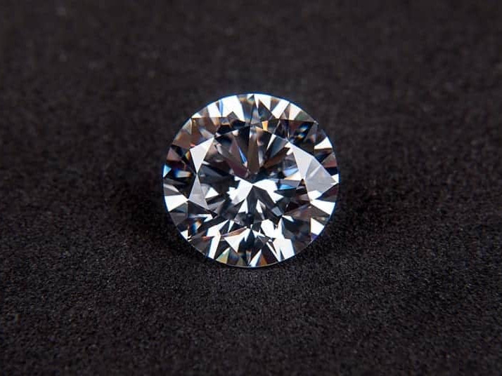 Sparkling round-cut diamond glistening on a dark background.