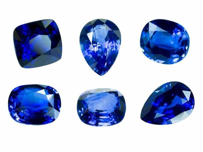 A collection of cut and polished sapphires showcasing various shapes and shades of deep blue.