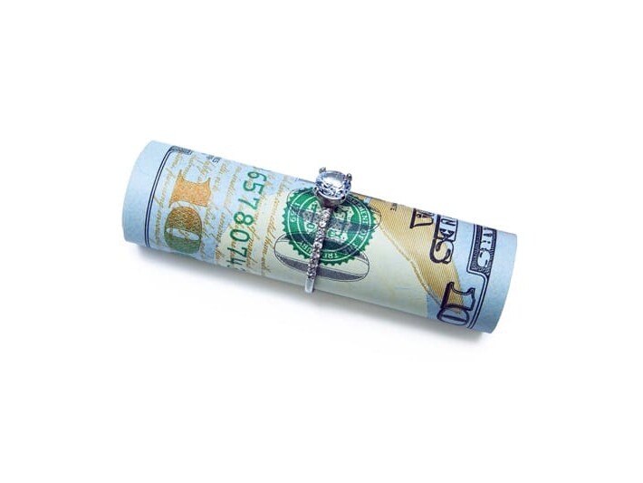 A rolled up us hundred-dollar bill secured with a rubber band, isolated on a white background.