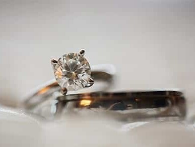 A close-up of a sparkling diamond engagement ring with a wedding band, both set against a soft, blurred background, symbolizing love and commitment.
