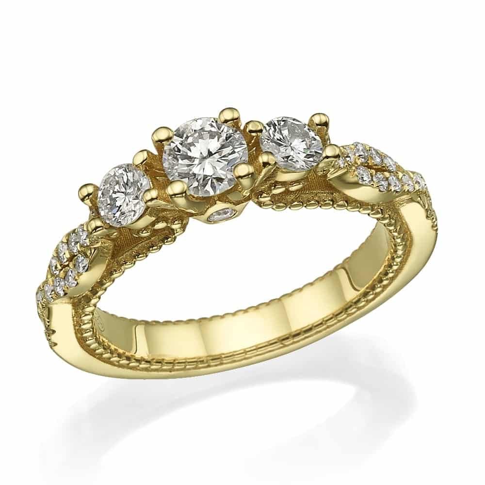 טבעת דגם ננסי מציגה שלישיית יהלומים נוצצים בחיתוך עגול במרכזו, משלימים הדגשות יהלומים משובצות לאורך הקצוות המורכבים של הלהקה.