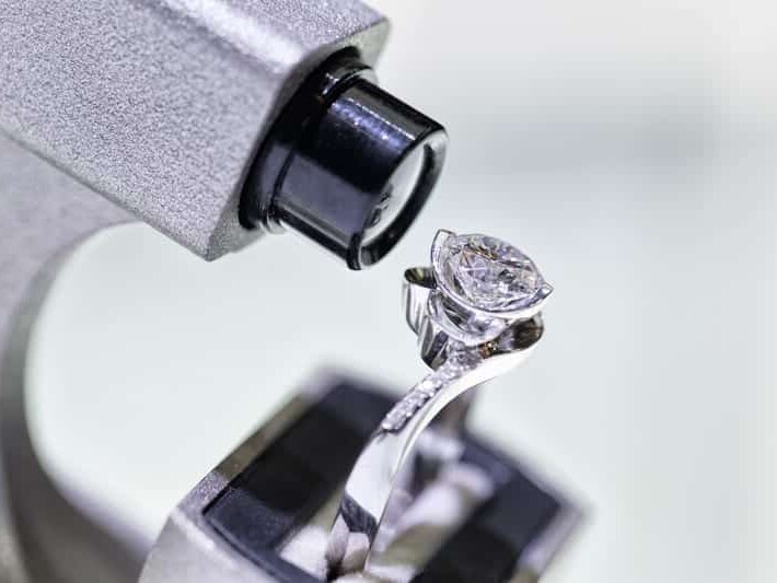 A diamond ring being closely inspected or evaluated under a jeweler's loupe.