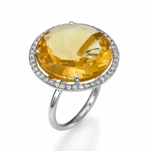 טבעת אבן חן סיטרין ויהלומים כסופה אלגנטית הכוללת אבן חן צהובה גדולה בחיתוך קורן מוקפת בהילה של יהלומים קטנים.