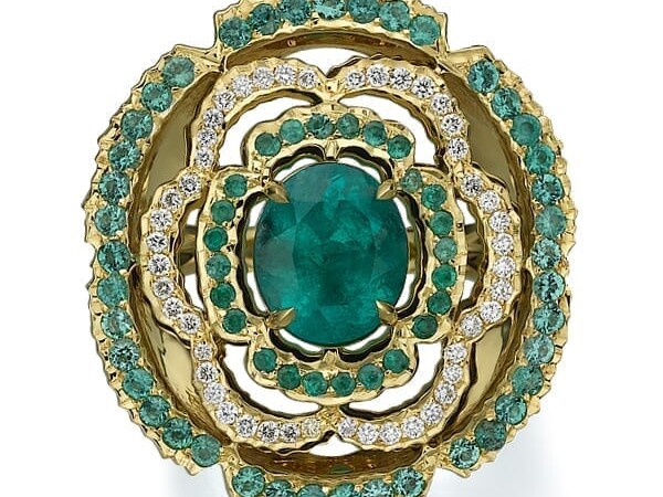 An intricate gold ring featuring a central oval emerald surrounded by concentric halos of smaller emeralds and diamonds, set in a detailed scalloped design.