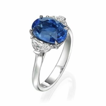 טבעת אלגנטית הכוללת ספיר כחול בחיתוך סגלגל גדול משובץ בין שני יהלומים נוצצים על רצועת כסף אלגנטית טבעת אבן חן ספיר דגם נלי.