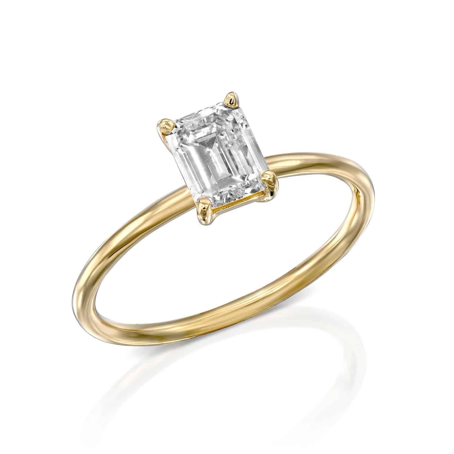 טבעת זהב אלגנטית הכוללת יהלום יחיד בחיתוך אמרלד, מבודדת על רקע לבן.