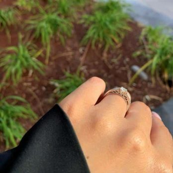 תקריב של יד עונדת טבעת יהלומים ירין, על רקע מטושטש של צמחים ירוקים.