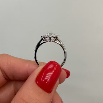 יד עם לק אדום מחזיקה טבעת יהלומים Sitvanit ב-25% הנחה על רקע ניטרלי.