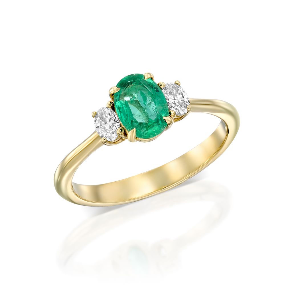 טבעת זהב הכוללת אזמרגד ירוק אליפסה מרכזית ולצדה שני יהלומים לבנים עגולים. לטבעת רצועה פשוטה ואלגנטית בגימור מלוטש.