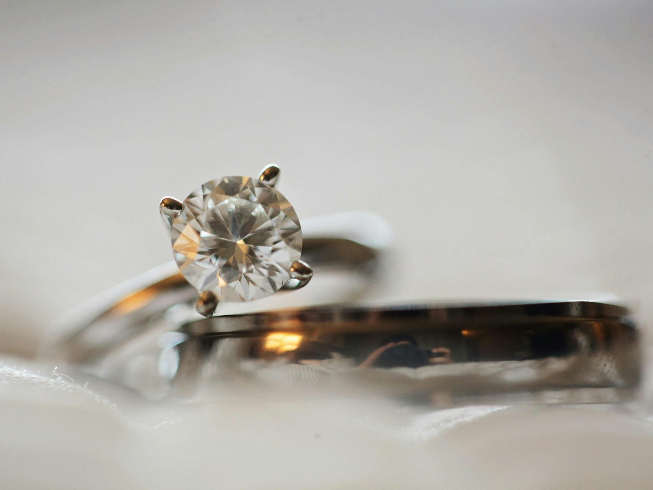 תקריב של טבעת אירוסין יהלום נקייה מונחת מעל רצועת נישואין תואמת, משובצת על רקע רך ומטושטש.